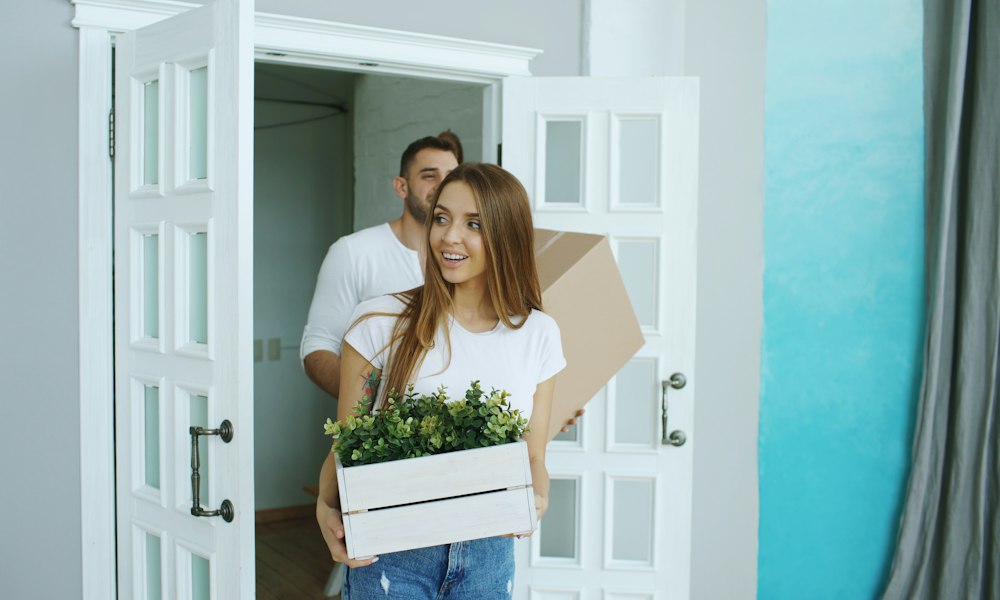 A couple carrying boxes into a new home